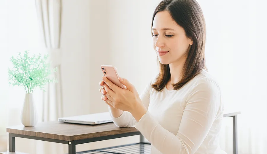 イメージ写真：リビングでスマホの画面を見ている